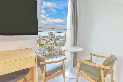 a room with a desk and chairs and a large window at Berith Hotel in Sokcho