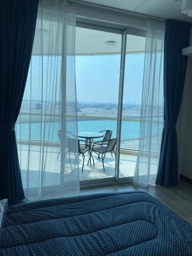 a bedroom with a table and a view of the ocean at cozy sea view one bedroom apartment in Dilmunia Island