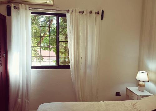 a bedroom with a window with white curtains and a bed at Amplio, cómodo y junto a la playa de Boca Chica in Boca Chica