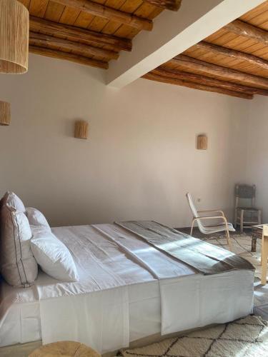 a large bed in a room with a chair at TOUGYA Ecolodge Near Agafay Desert in Marrakech