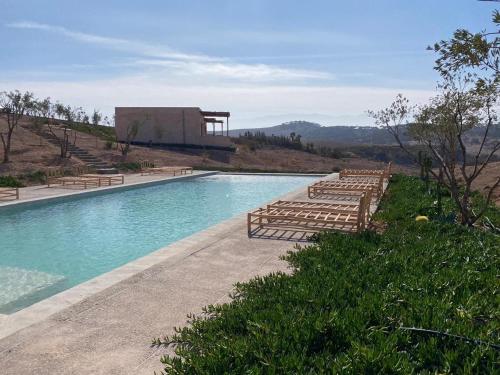 a swimming pool with wooden loungers next to a building at TOUGYA Ecolodge Near Agafay Desert in Marrakech