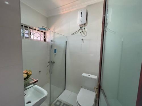 a bathroom with a shower and a toilet and a sink at Park Springs Hotel in Cape Coast
