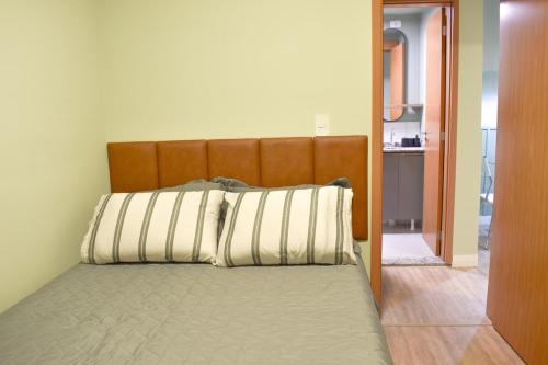 Una cama con cabecero de madera en una habitación. en Apartamento Novo em Londrina, en Londrina