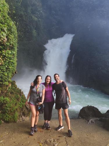 three people standing in front of a waterfall at Casamar in Cobán