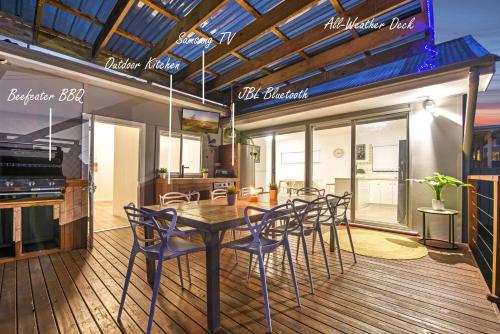 a dining room with a table and chairs on a deck at Kookaburra Krib Walk 2 Little Beach and Shoal Bay in Nelson Bay