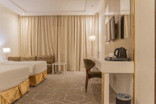 a hotel room with two beds and a desk at Sela Hotel فندق صلة in Medina