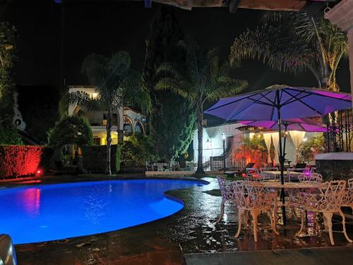 a pool at night with tables and an umbrella at Suites H la ermita in San Miguel de Allende