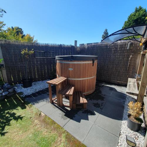 a wooden hot tub and a bench in a backyard at Moe Marie Sleep Peacefully in Turangi