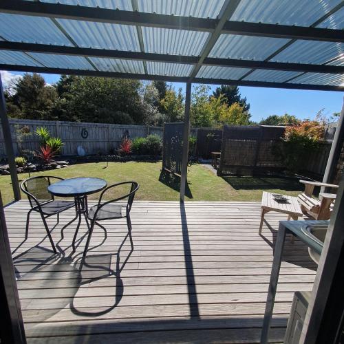 a patio with a table and chairs on a deck at Moe Marie Sleep Peacefully in Turangi