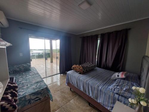 a bedroom with a bed and a sliding glass door at Casa da lagoa com rampa para embarcações in Tramandaí