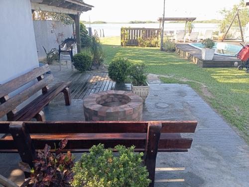 a group of wooden benches sitting next to a fire pit at Casa da lagoa com rampa para embarcações in Tramandaí