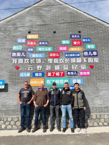a group of men standing in front of a wall with signs at Gubeikou Great Wall Yunyeshu Boutique Guesthome in Miyun