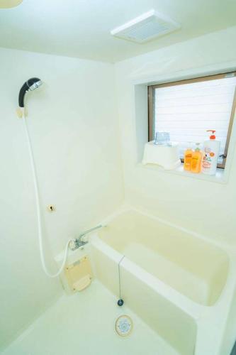 a white bathroom with a tub and a sink at Ohana in Minami Aso