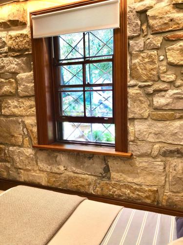 a window in a stone wall next to a bed at Stone 1Bedroom Cottage in Sydney