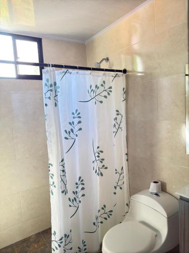 a bathroom with a toilet and a shower curtain at House Villa Las Marias in Juan de Acosta