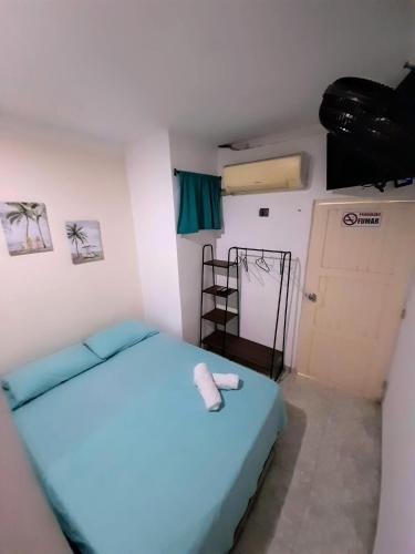 a small room with a blue bed and a door at Rivera Hostel in Santa Marta