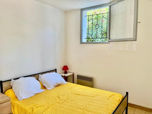 une chambre avec un lit jaune et une fenêtre dans l'établissement Appartement 2 pièces à Sète, 500m de la plage, terrasse, parking, animaux admis - FR-1-338-336, à Sète