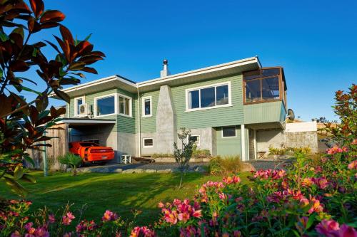a green house with a yard with flowers at Classic Charm Sea & Mountain Views in Kaikoura