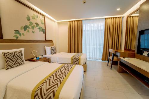 a hotel room with two beds and a flat screen tv at Boracay Haven Suites in Boracay