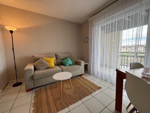 un salon avec un canapé et une table dans l'établissement Appartement avec Terrasse Proche Plage et Parking Gratuit - FR-1-239-955, à Urrugne