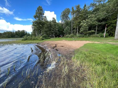 a body of water with some grass and trees at House with playground visit Isaberg and High Chaparral in Dannäs