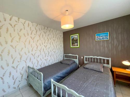 deux lits jumeaux dans une chambre avec un mur dans l'établissement Charmante maison 2 chambres, proche plage, commerces, avec terrasse et WiFi à Saint-Jean-de-Monts - FR-1-323-284, à Saint-Jean-de-Monts