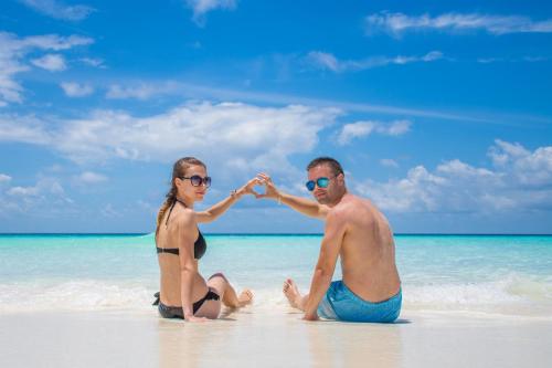 a man and a woman sitting on a beach at Madi Maldives Ukulhas in Ukulhas