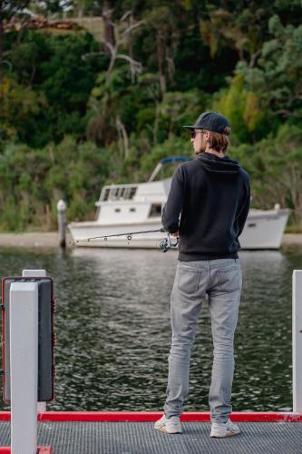 a man standing on a dock with a boat in the water at Candlebark at Boardwalk Villas in Metung