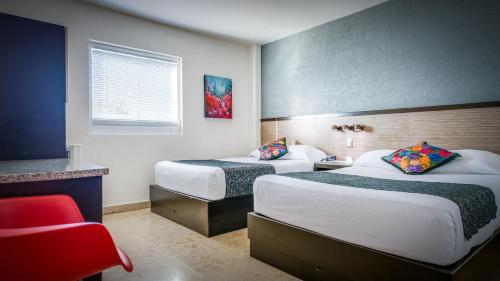 a hotel room with two beds and a red chair at Homesuites Rotarismo in Culiacán