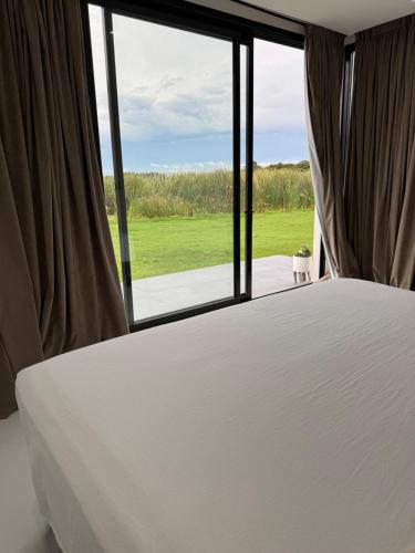 une chambre avec un lit et une grande fenêtre dans l'établissement Casa con Piscina sobre Laguna Brava - Tranquilidad y Naturaleza en Barrio Privado, à Corrientes