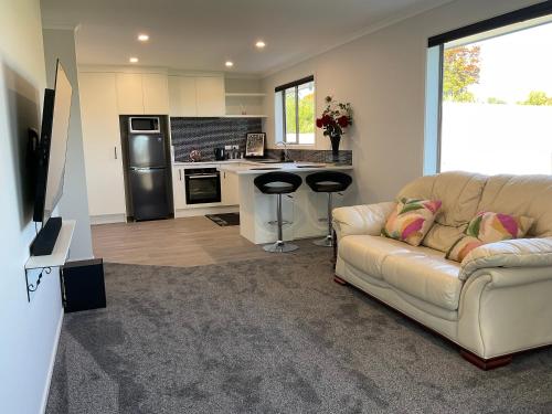 a living room with a couch and a kitchen at Di Lusso Lansdowne in Masterton