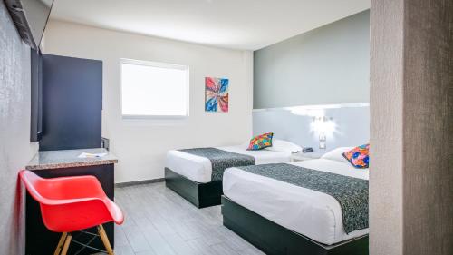 a hotel room with two beds and a red chair at Homesuites Rotarismo in Culiacán