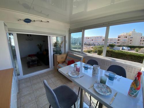 une salle à manger avec une table, des chaises et des fenêtres dans l'établissement Port Leucate : Appartement T3 Lumineux pour 4 Pers, Climatisation, Parking - FR-1-798-57, à Leucate