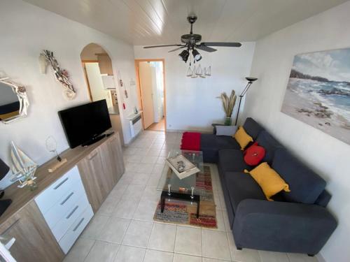 un salon avec un canapé bleu et une télévision dans l'établissement Port Leucate : Appartement T3 Lumineux pour 4 Pers, Climatisation, Parking - FR-1-798-57, à Leucate