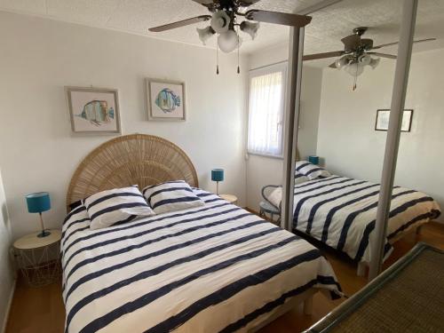 une chambre avec deux lits et un ventilateur de plafond dans l'établissement Port Leucate : Appartement T3 Lumineux pour 4 Pers, Climatisation, Parking - FR-1-798-57, à Leucate