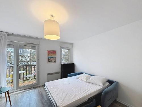 une chambre avec un lit et une grande fenêtre dans l'établissement Charmant T1 avec balcon près plage et centre Cabourg - FR-1-465-126, à Cabourg