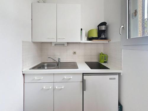 une cuisine avec des armoires blanches et un évier dans l'établissement Charmant T1 avec balcon près plage et centre Cabourg - FR-1-465-126, à Cabourg