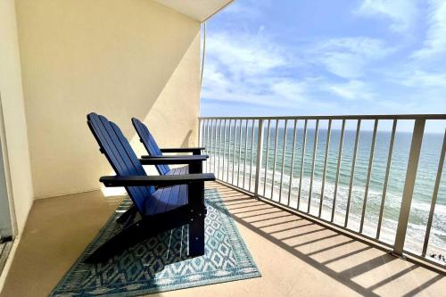 two blue chairs sitting on a balcony looking at the ocean at Crystal Shores1006 condo in Gulf Shores