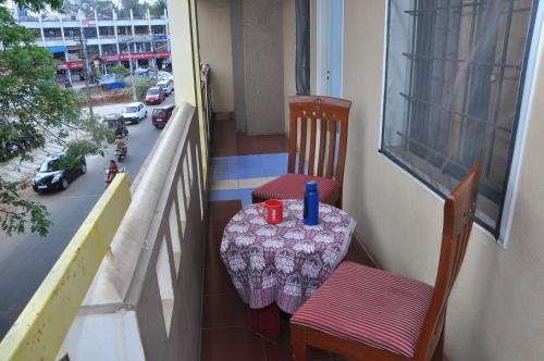 a table and chairs on a balcony with a view of a street at Vinayaka Deluxe Lodge in Kushālnagar