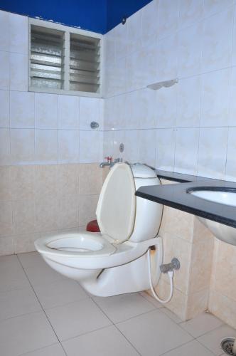 a bathroom with a toilet and a sink at Vinayaka Deluxe Lodge in Kushālnagar