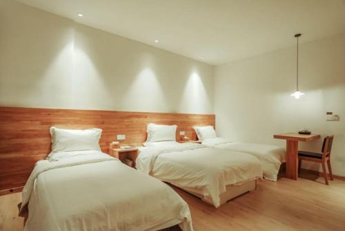 a bedroom with two beds and a table and a desk at Villa EN Emerald Valley, Huangshan in Huangshan Scenic Area