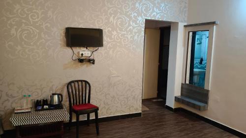 a room with a chair and a tv on a wall at Hotel Kiara Eshosans Palace in Shirdi