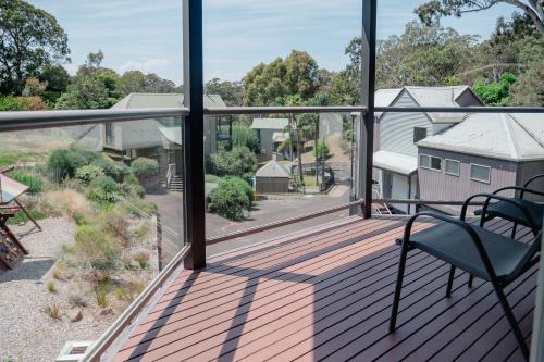 a balcony with a chair and a view of a yard at Kidman at Boardwalk Villas in Metung