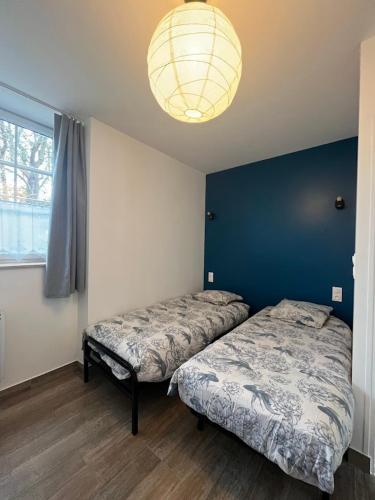 une chambre avec deux lits et un mur bleu dans l'établissement 14 bis Les Gîtes Bigoudens, à Plonéour-Lanvern