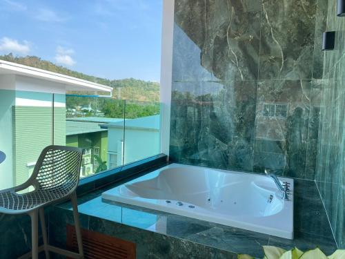 a bath tub in a room with a chair at Mountain breeze villa phuket in Ban Bang Khu