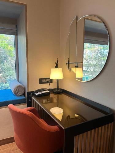 a room with a desk with a chair and a mirror at Pride Hotel Pune in Pune