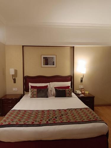 a large bed in a hotel room with two lamps at Pride Hotel Pune in Pune