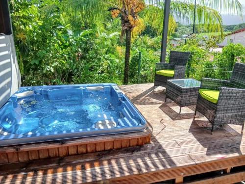 a hot tub on a deck with chairs and a table at Maison charmante proche de Petit-Bourg avec vue montagne in Petit-Bourg
