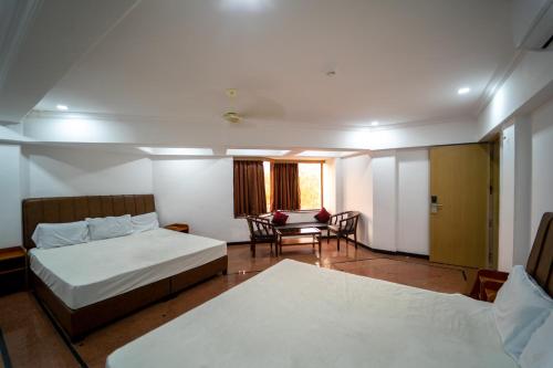 a hotel room with two beds and a table and chairs at Hotel Kewal in Nashik