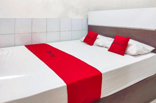 ein Bett mit zwei roten Kissen darauf in der Unterkunft RedDoorz at DST RSU Banjar Guest House Syariah in Pataruman